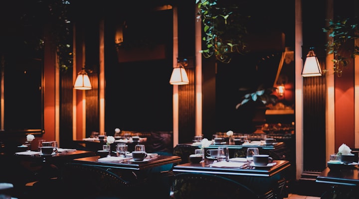 Hotel restaurant dining room in the evening, tables set with warm lamps